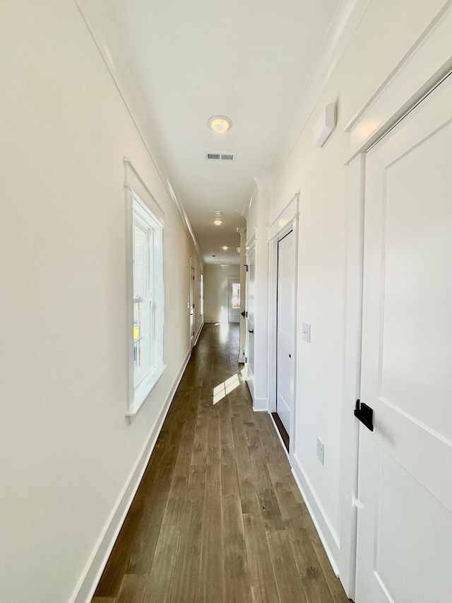 corridor with dark wood-type flooring, visible vents, and baseboards