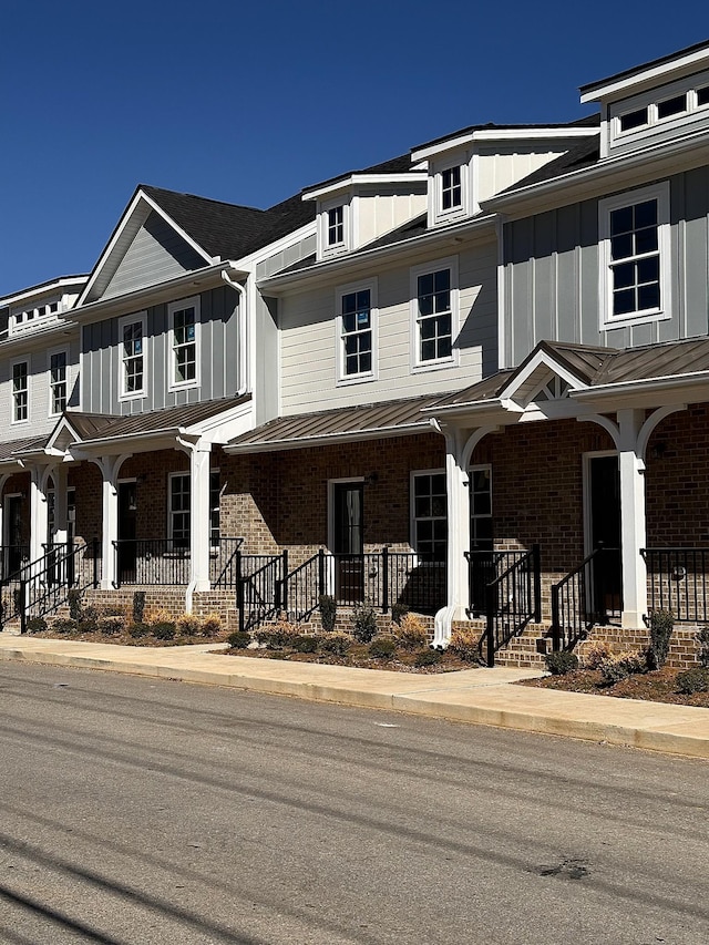 multi unit property featuring a standing seam roof, a porch, board and batten siding, and brick siding