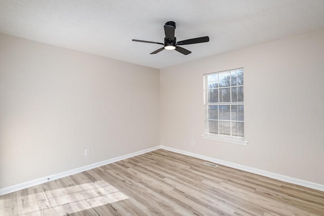 unfurnished room with baseboards, visible vents, ceiling fan, a textured ceiling, and light wood-style floors