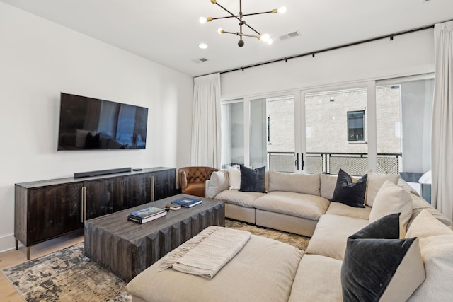 living room with french doors, wood finished floors, visible vents, and an inviting chandelier