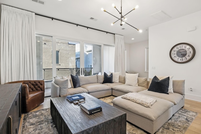 living room featuring a chandelier, wood finished floors, visible vents, and baseboards