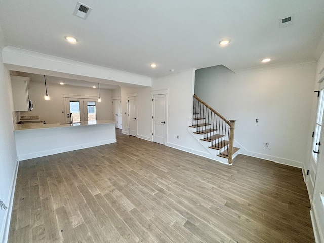 unfurnished living room featuring stairs, wood finished floors, a sink, and visible vents