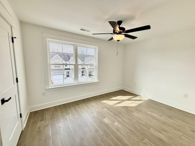 empty room featuring baseboards, visible vents, and wood finished floors