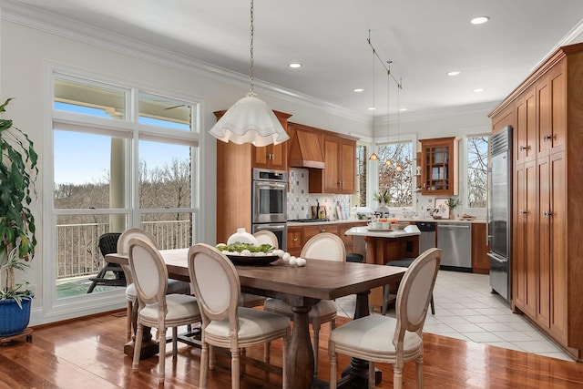 dining area with ornamental molding, light wood-style floors, and plenty of natural light