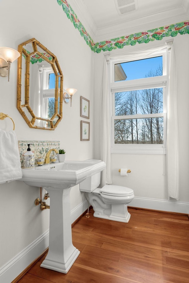 bathroom with toilet, baseboards, ornamental molding, and wood finished floors