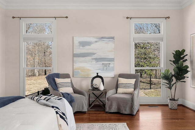 bedroom with baseboards, wood finished floors, visible vents, and crown molding