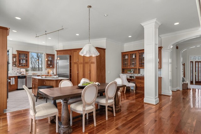 dining space with arched walkways, recessed lighting, ornate columns, and wood finished floors