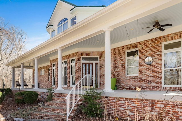 doorway to property with a porch, brick siding, and a ceiling fan