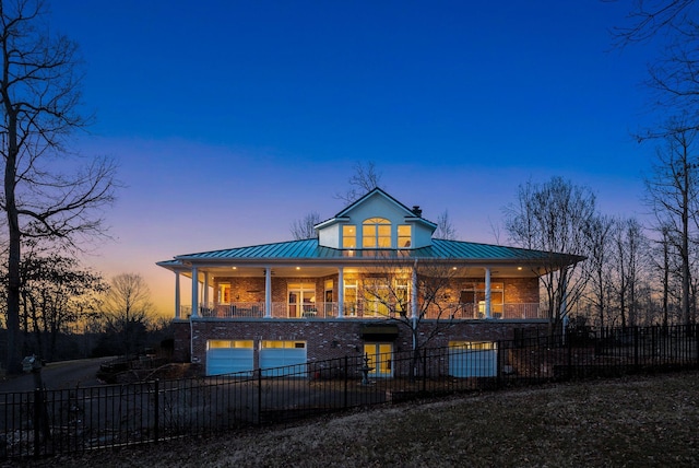 view of front of house featuring metal roof, a fenced front yard, a balcony, a garage, and a standing seam roof