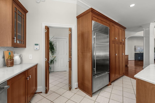 kitchen with light tile patterned floors, arched walkways, stainless steel appliances, and crown molding