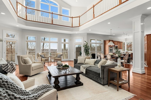 living area featuring ornamental molding, recessed lighting, decorative columns, and wood finished floors