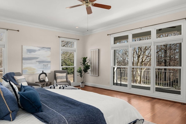 bedroom featuring ceiling fan, crown molding, baseboards, and wood finished floors