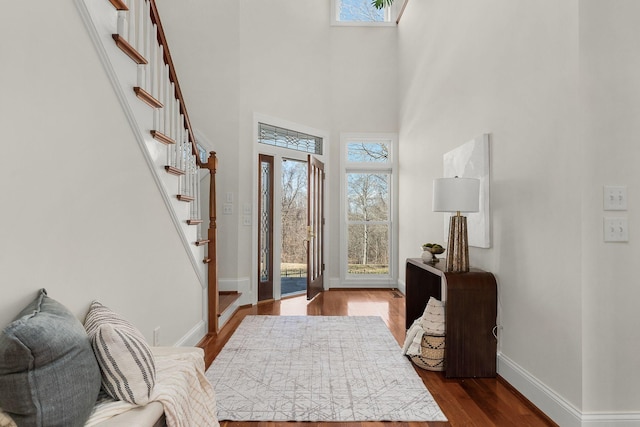 foyer with stairs, a high ceiling, dark wood finished floors, and baseboards