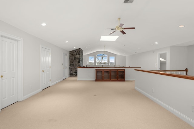 unfurnished living room with lofted ceiling with skylight, visible vents, baseboards, and light colored carpet