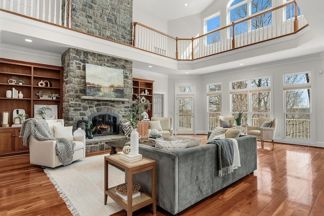 living area with hardwood / wood-style floors, a fireplace, a towering ceiling, and crown molding