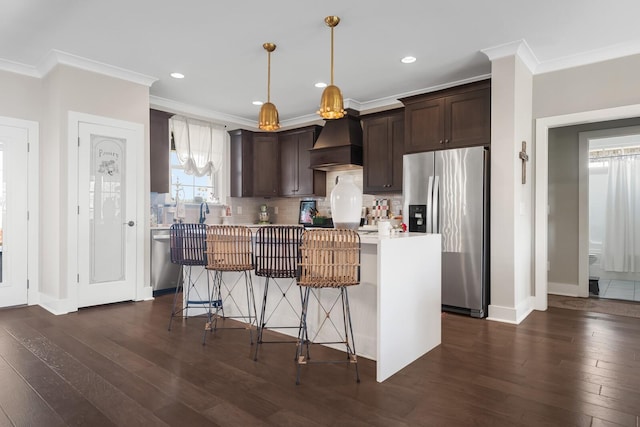 kitchen featuring stainless steel appliances, premium range hood, light countertops, dark brown cabinets, and tasteful backsplash