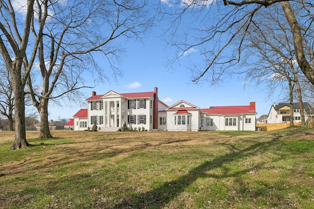 neoclassical / greek revival house with a chimney and a front lawn