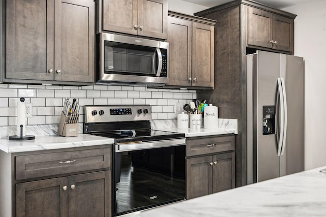 kitchen featuring stainless steel appliances, dark brown cabinetry, light stone counters, and tasteful backsplash