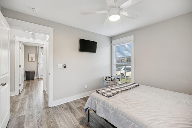 bedroom with ceiling fan, light wood finished floors, and baseboards