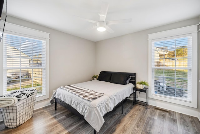 bedroom with ceiling fan, wood finished floors, and baseboards