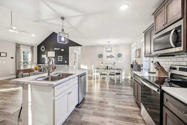 kitchen featuring appliances with stainless steel finishes, backsplash, light wood-type flooring, and a sink