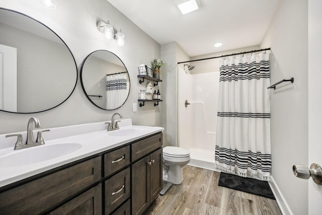 bathroom featuring double vanity, a sink, toilet, and wood finished floors