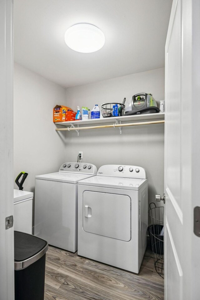 washroom featuring washing machine and dryer, laundry area, and wood finished floors