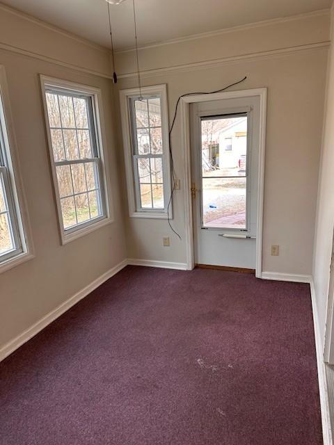 unfurnished room with baseboards, dark carpet, and crown molding