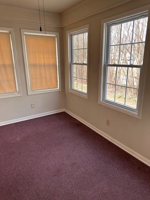 spare room with dark carpet and baseboards