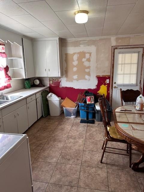 kitchen featuring light tile patterned floors, light countertops, stove, white cabinets, and a sink