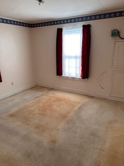 empty room featuring light colored carpet and baseboards