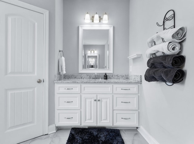 bathroom with marble finish floor, vanity, and baseboards