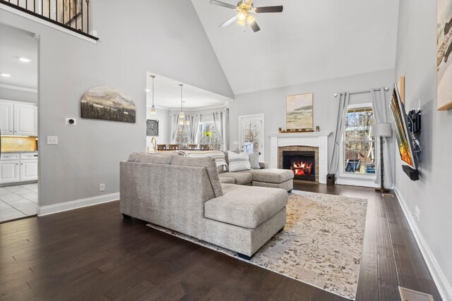 living room featuring a fireplace, baseboards, dark wood finished floors, and a wealth of natural light