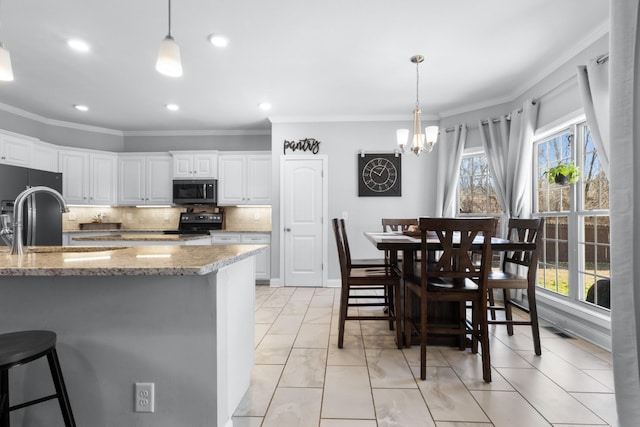 kitchen featuring stainless steel microwave, backsplash, white cabinetry, a sink, and black range with electric cooktop