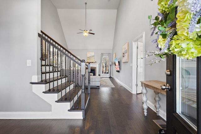 foyer entrance with stairway, a fireplace, wood finished floors, and baseboards