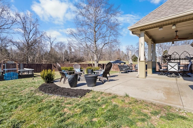 view of yard with a ceiling fan, fence, a fire pit, and a patio