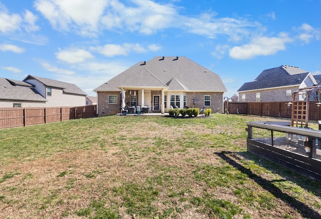 back of property with a patio area, a fenced backyard, a lawn, and brick siding