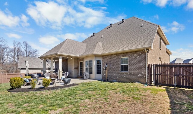 back of property featuring a patio area, roof with shingles, a lawn, and brick siding