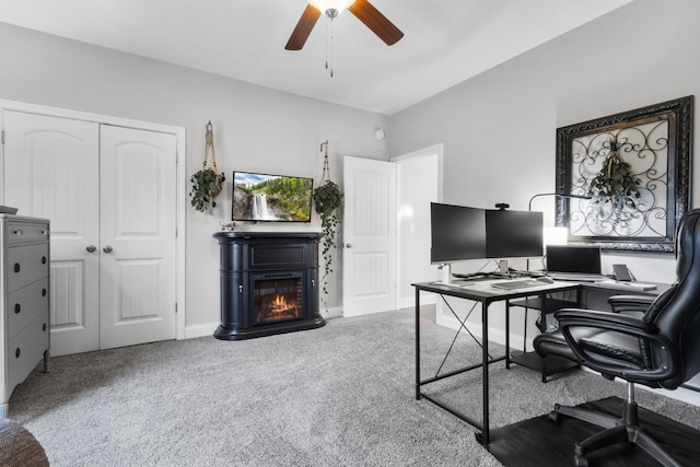 office area with carpet, a glass covered fireplace, a ceiling fan, and baseboards