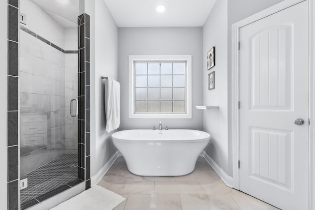 bathroom featuring a freestanding bath, marble finish floor, a shower stall, and baseboards