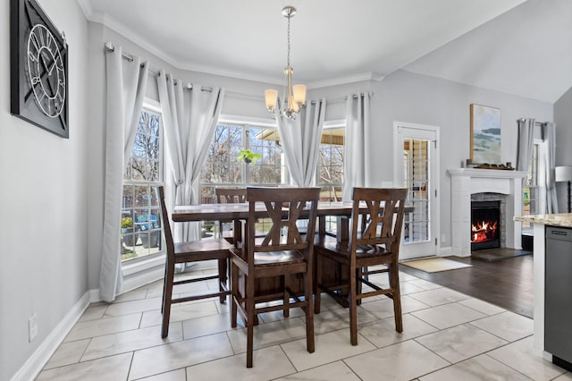 dining room featuring ornamental molding, a warm lit fireplace, a notable chandelier, and baseboards