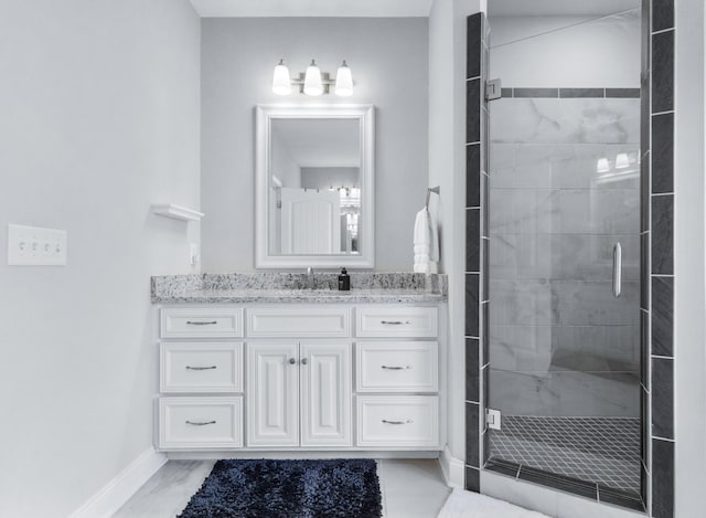 full bathroom with a stall shower, vanity, and baseboards