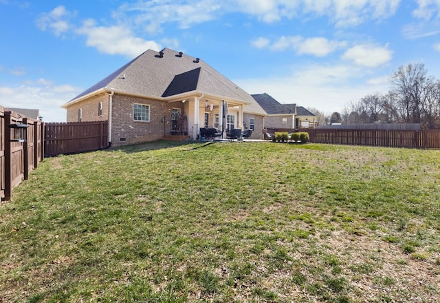 rear view of property featuring a fenced backyard, brick siding, a shingled roof, crawl space, and a lawn