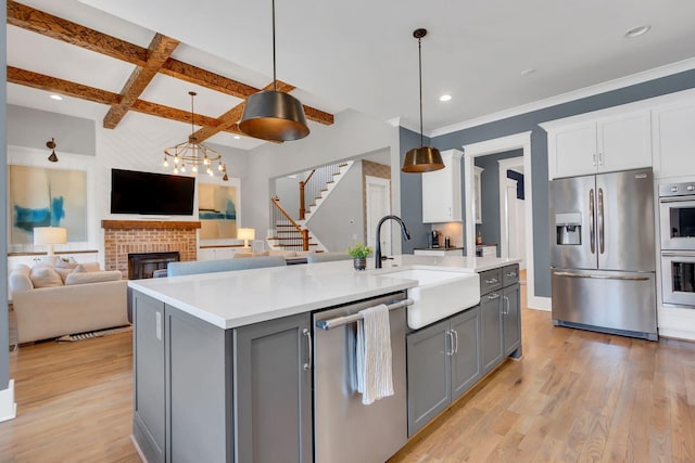 kitchen with appliances with stainless steel finishes, gray cabinets, coffered ceiling, and a sink