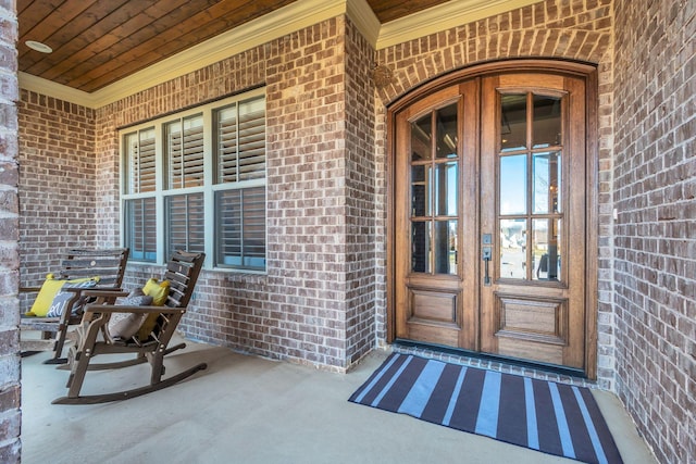 doorway to property with a porch, french doors, and brick siding