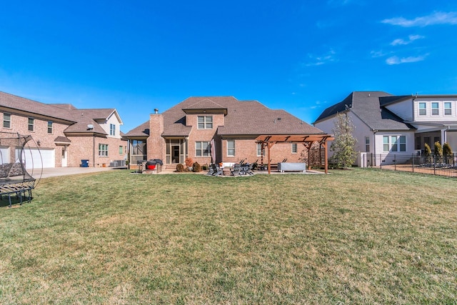 rear view of property featuring a trampoline, fence, a yard, a patio area, and brick siding