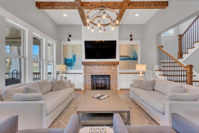 living area with light wood finished floors, stairs, a fireplace, and beamed ceiling