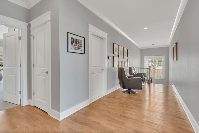 living area with light wood-type flooring, crown molding, and baseboards