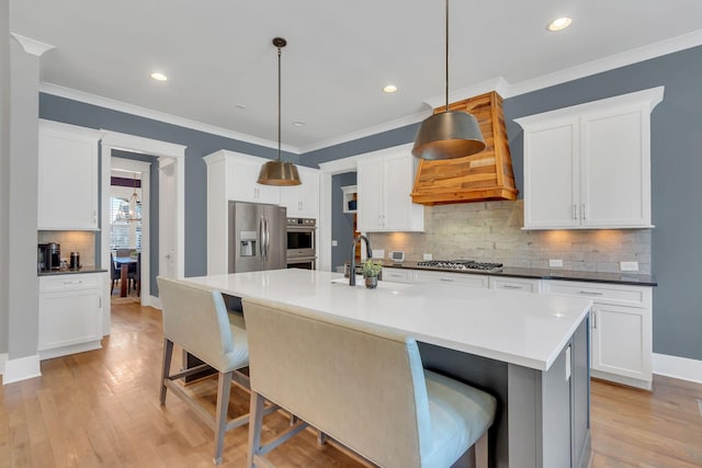 kitchen featuring light wood finished floors, appliances with stainless steel finishes, a breakfast bar, and crown molding