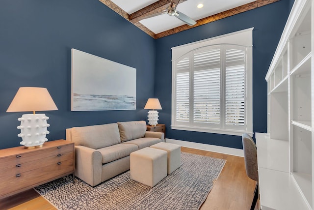 living area featuring ceiling fan, beamed ceiling, wood finished floors, and baseboards